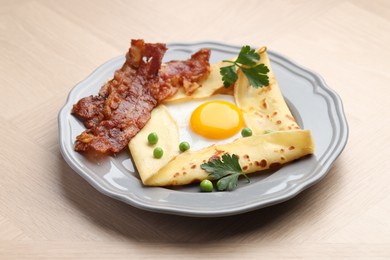 Photo of Delicious crepe with egg, bacon and green peas on wooden table. Breton galette