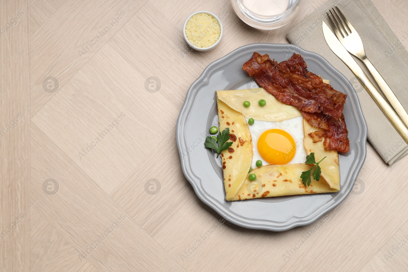 Photo of Delicious crepe with egg, bacon and green peas served on wooden table, flat lay. Space for text