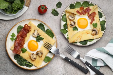 Photo of Delicious crepes with eggs, bacon and mushrooms served on grey table, flat lay. Breton galette