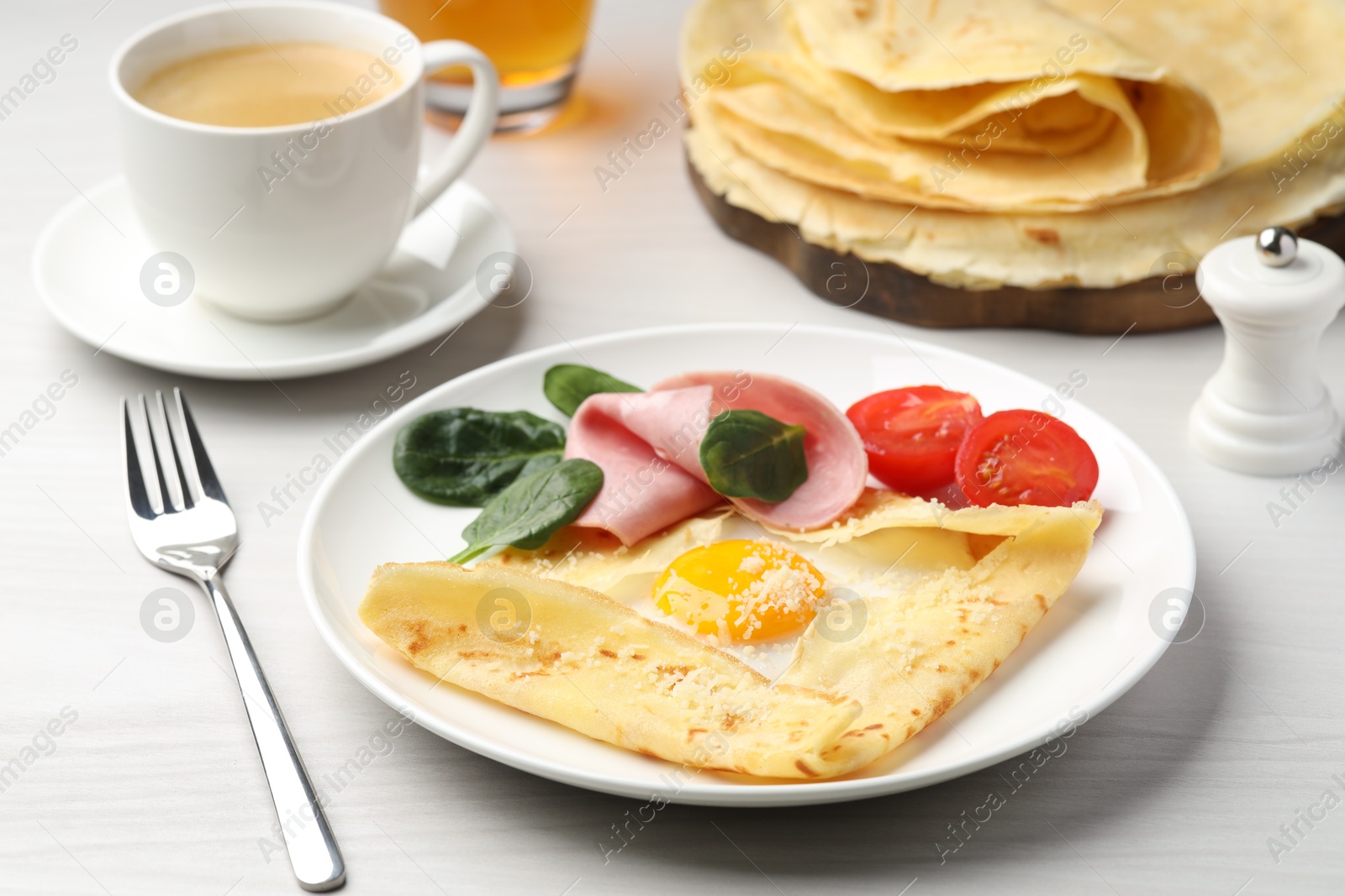 Photo of Delicious crepe with egg, ham and parmesan cheese served on white wooden table, closeup