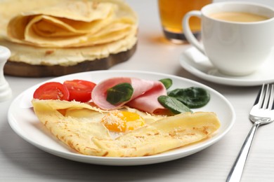 Photo of Delicious crepe with egg, ham and parmesan cheese served on white wooden table, closeup