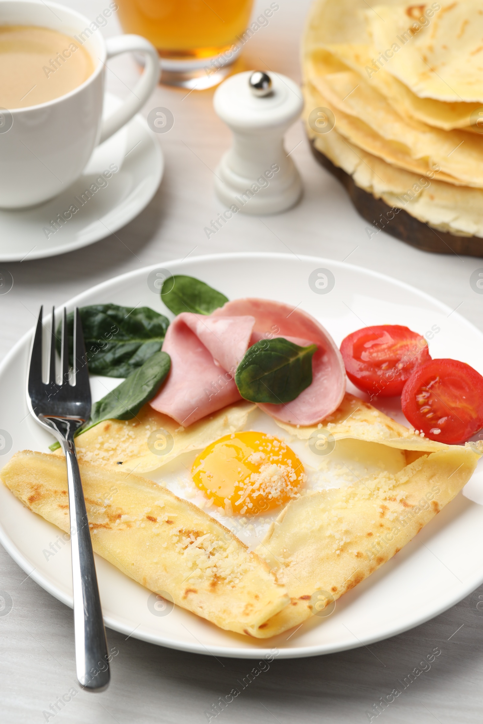 Photo of Delicious crepe with egg, ham and parmesan cheese served on white wooden table, closeup