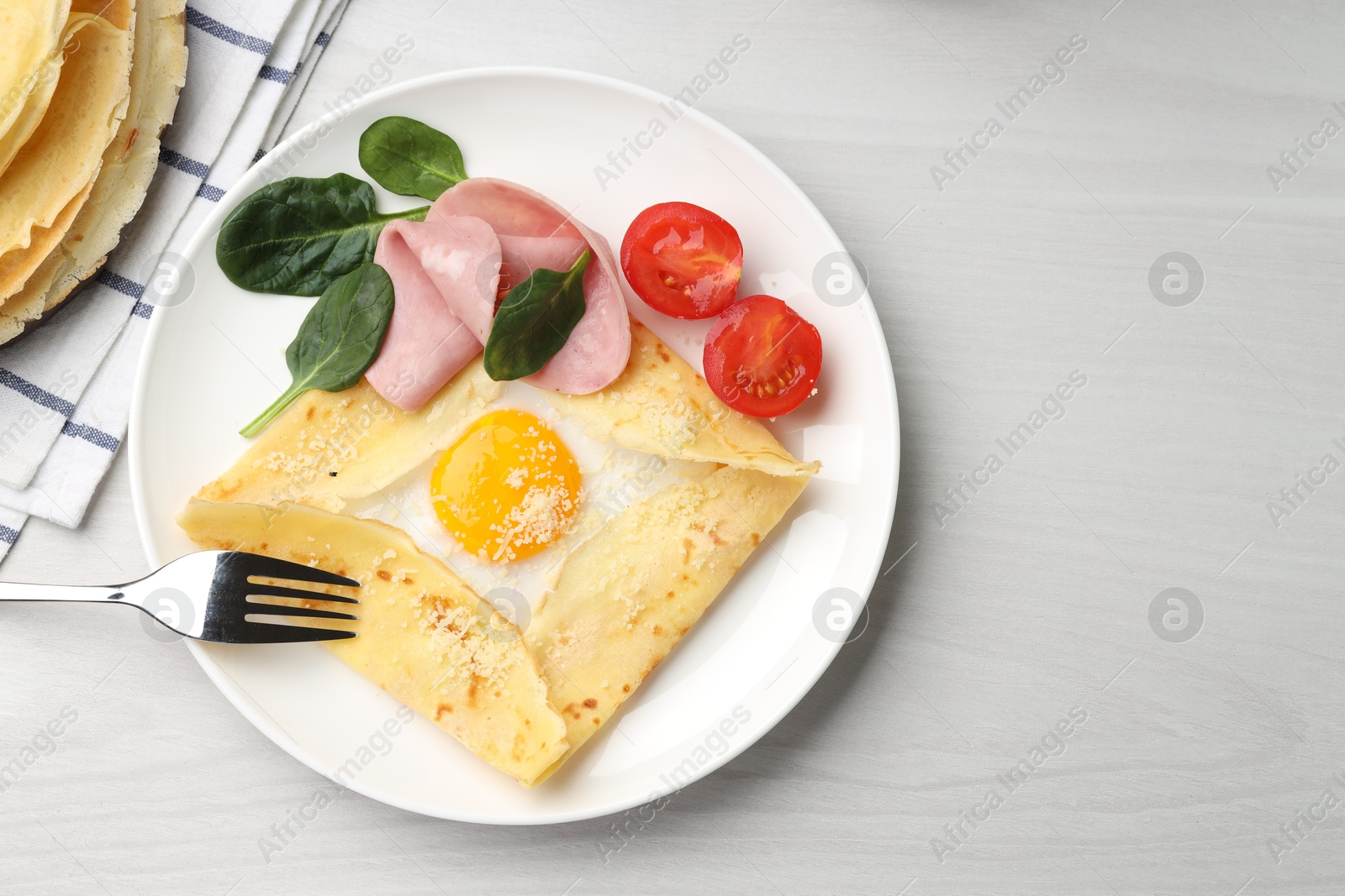 Photo of Delicious crepe with egg, ham and parmesan cheese served on light wooden table, flat lay. Space for text