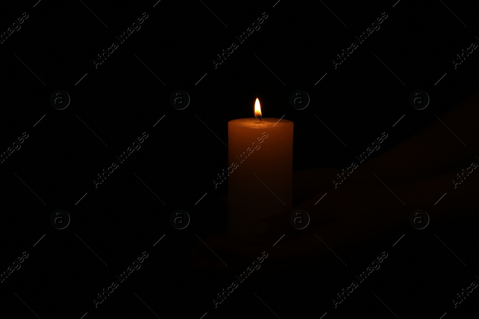 Photo of One burning church candle on dark background