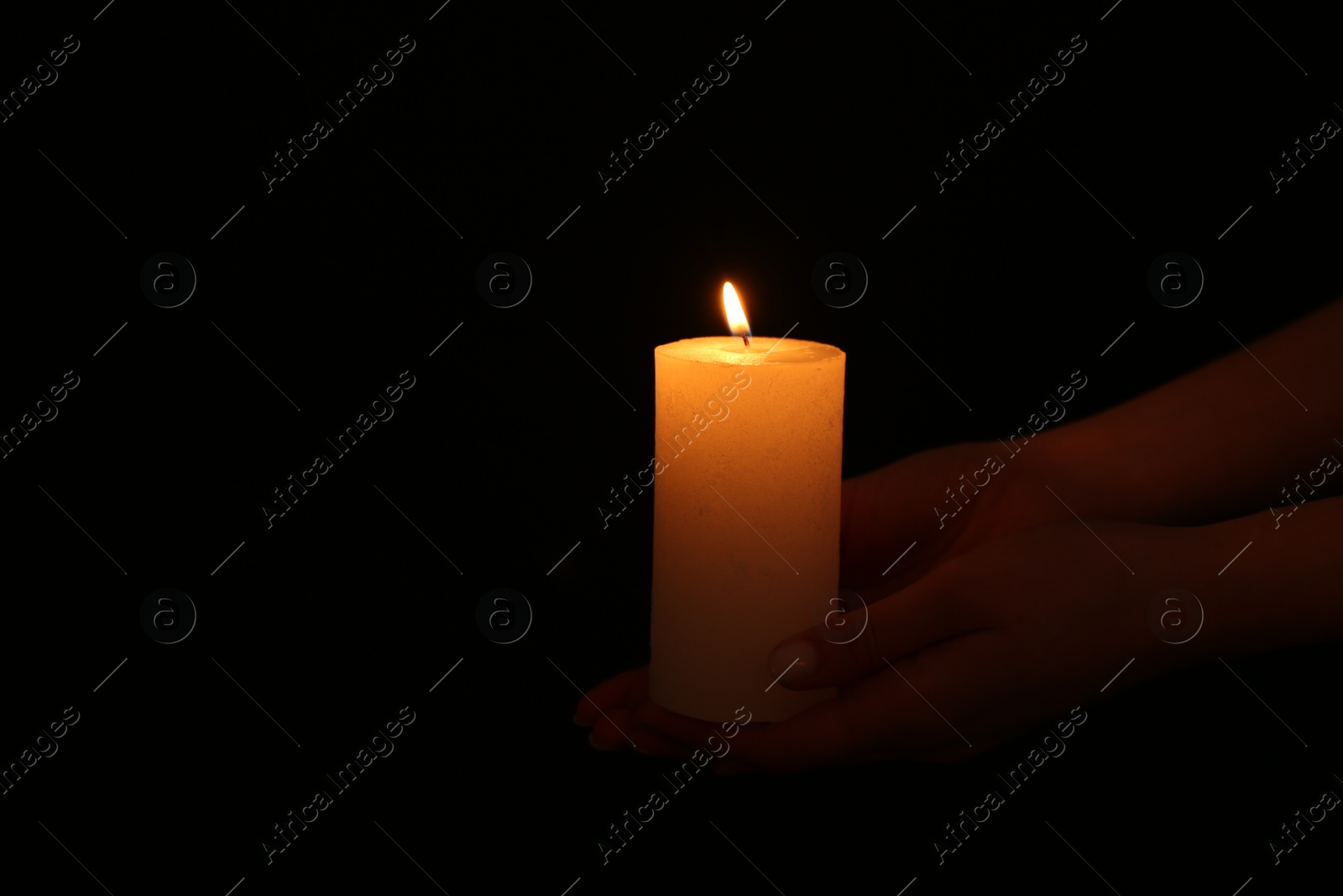 Photo of Woman with burning candle on dark background, closeup. Space for text