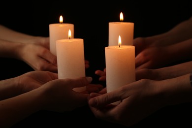 Photo of Women with burning candles on dark background, closeup