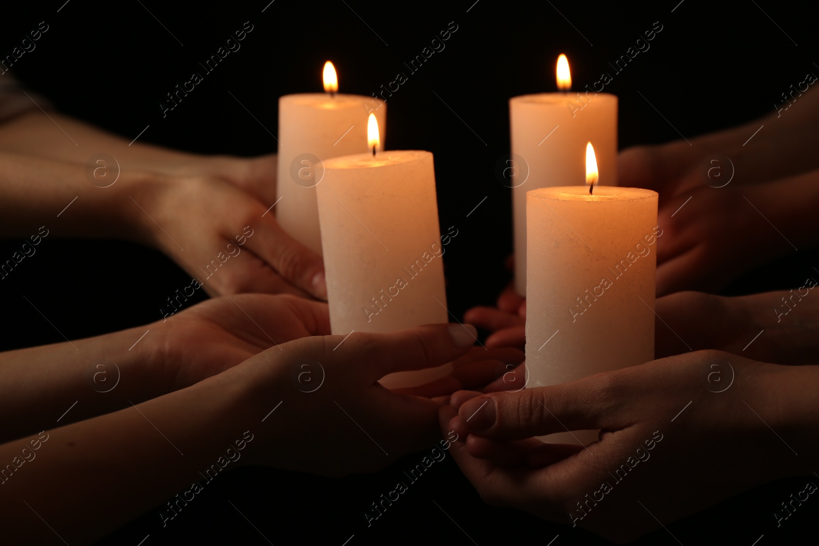 Photo of Women with burning candles on dark background, closeup