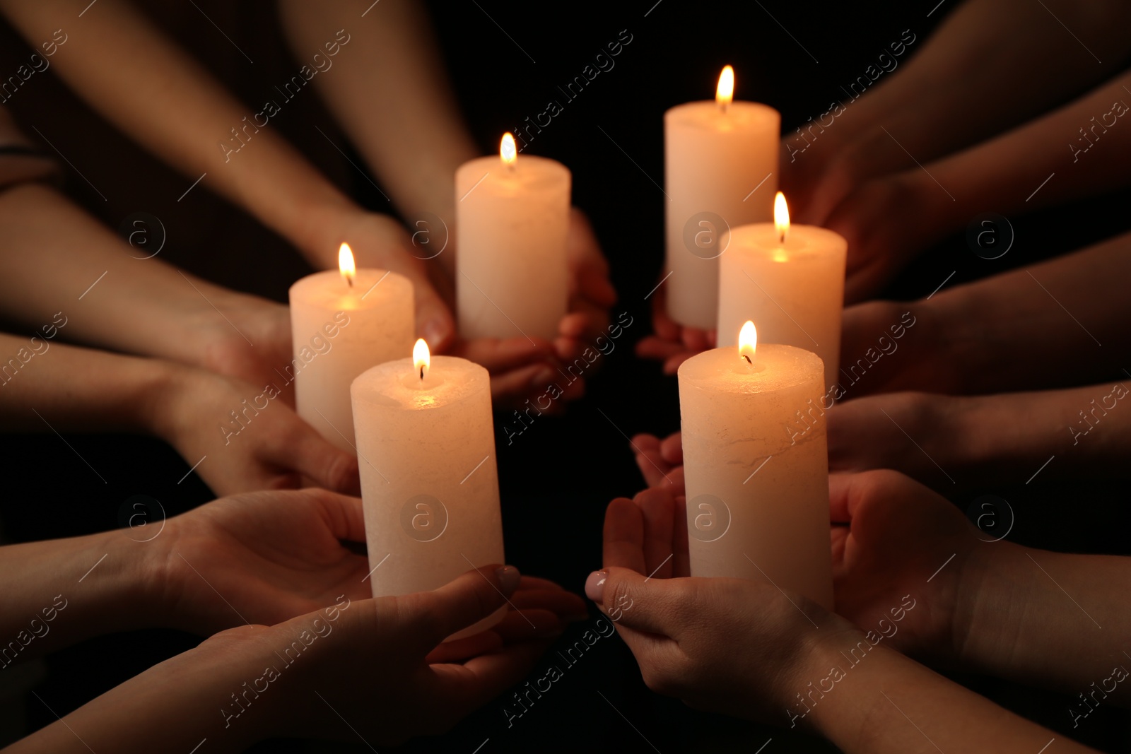 Photo of Women with burning candles on dark background, closeup