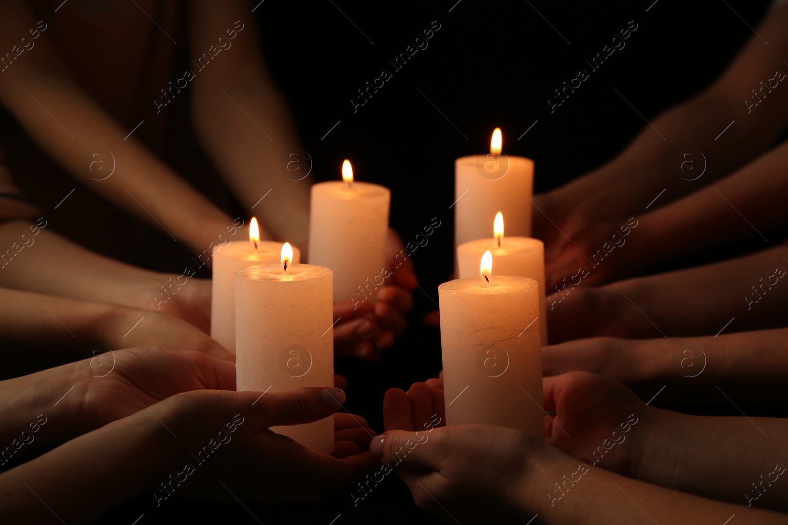 Photo of Women with burning candles on dark background, closeup