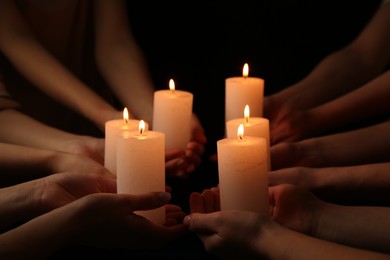 Photo of Women with burning candles on dark background, closeup