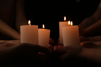 Photo of Women with burning candles on dark background, closeup