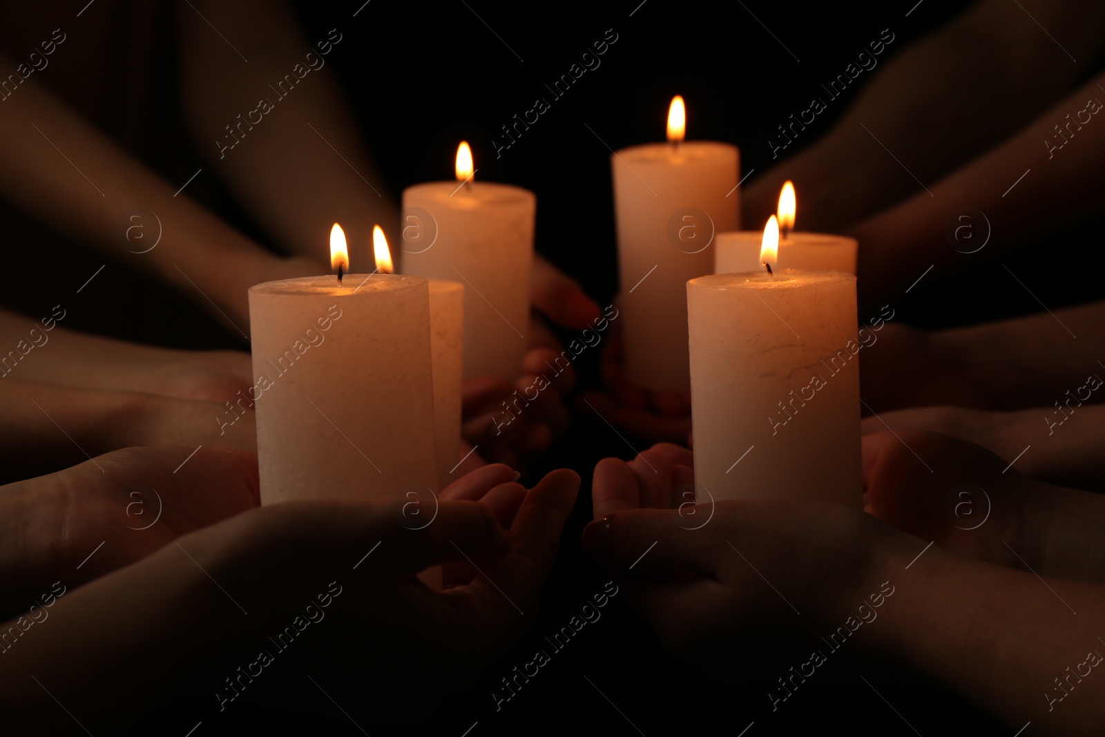 Photo of Women with burning candles on dark background, closeup