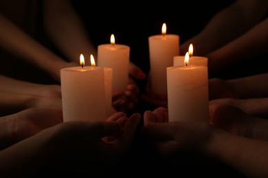 Photo of Women with burning candles on dark background, closeup