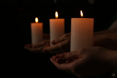 Photo of Women with burning candles on dark background, closeup