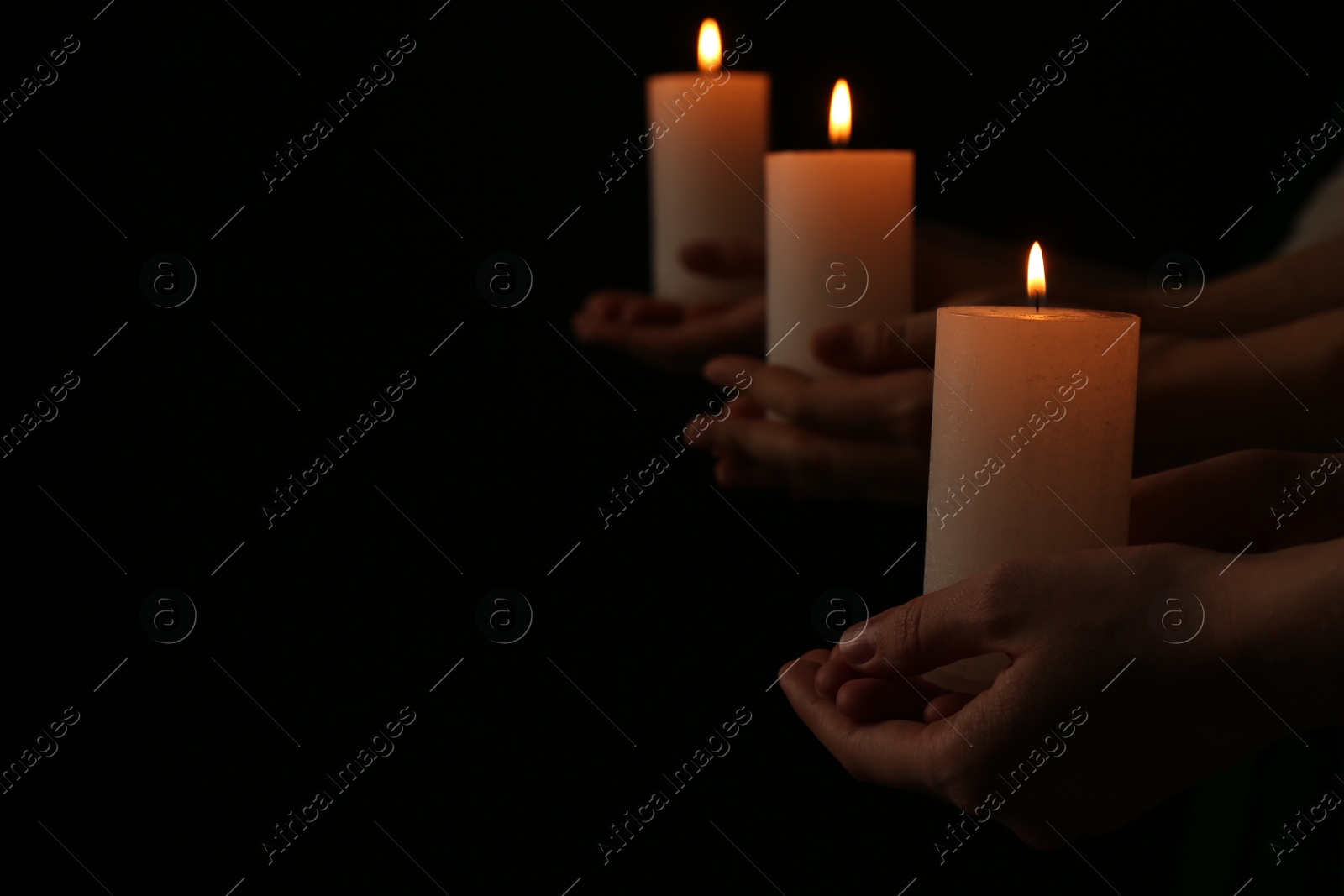 Photo of Women with burning candles on dark background, closeup. Space for text