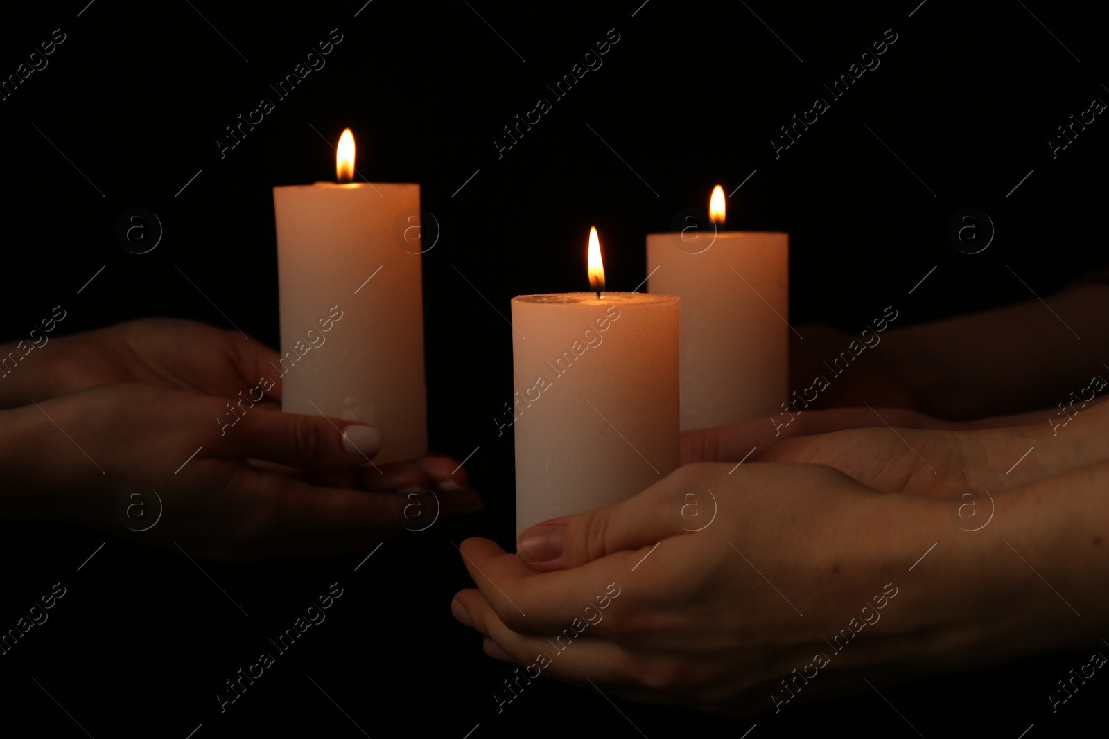 Photo of Women with burning candles on dark background, closeup