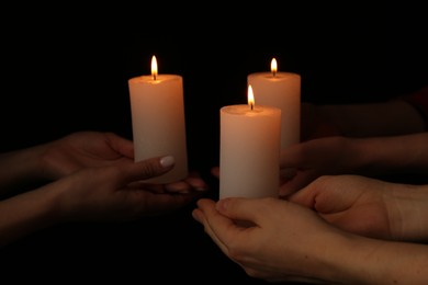 Photo of Women with burning candles on dark background, closeup