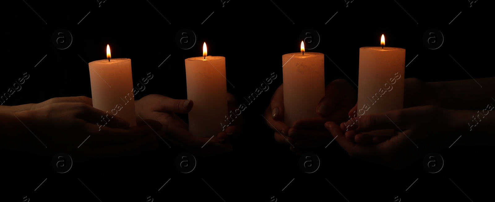 Photo of Women with burning candles on dark background, closeup