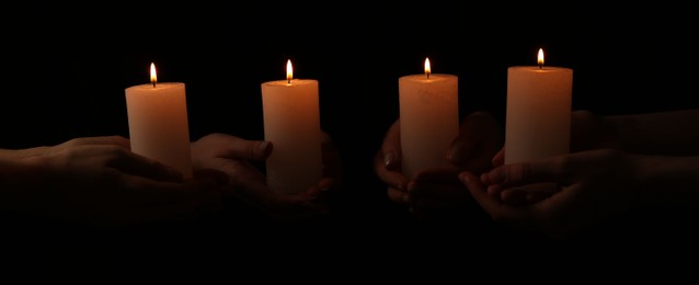 Photo of Women with burning candles on dark background, closeup