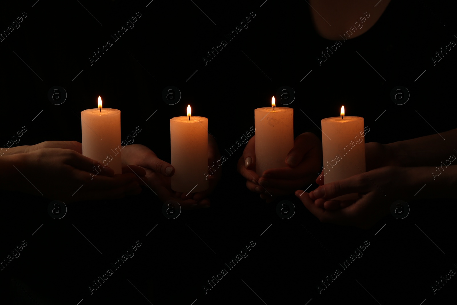 Photo of Women with burning candles on dark background, closeup