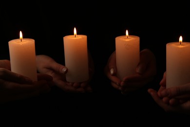 Photo of Women with burning candles on dark background, closeup