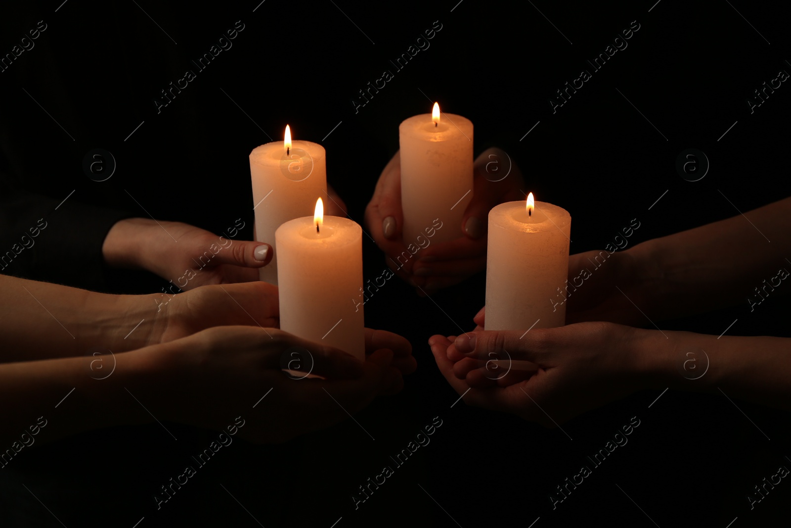 Photo of Women with burning candles on dark background, closeup