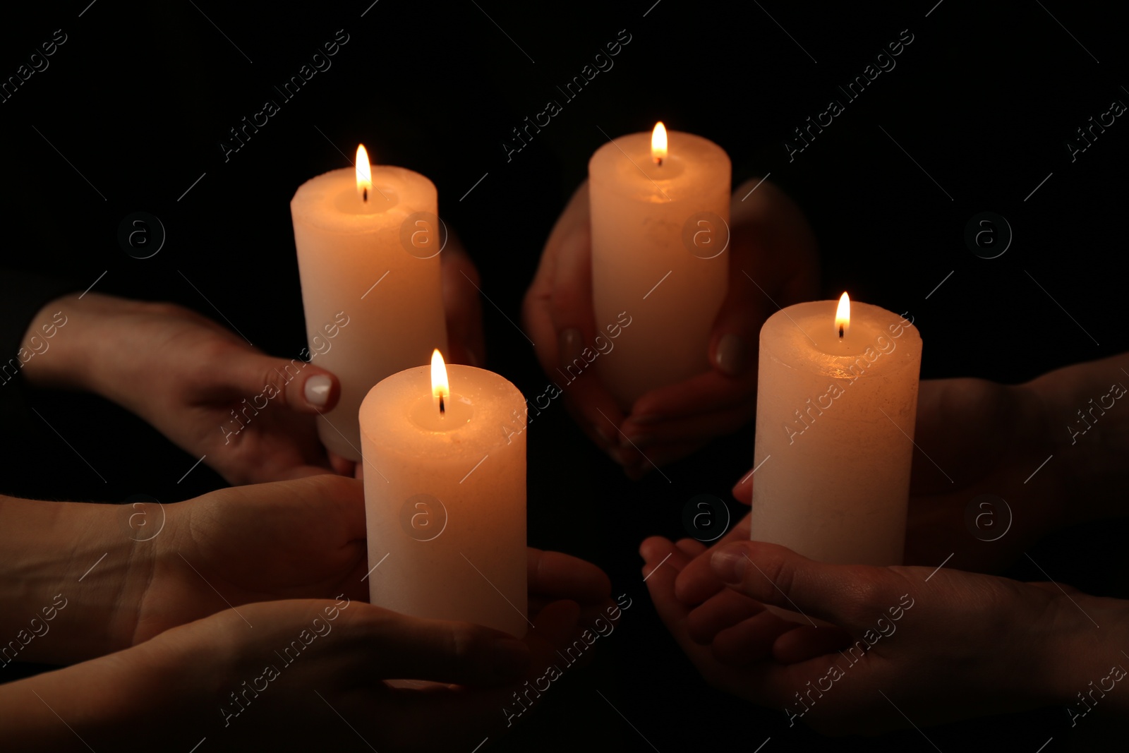 Photo of Women with burning candles on dark background, closeup