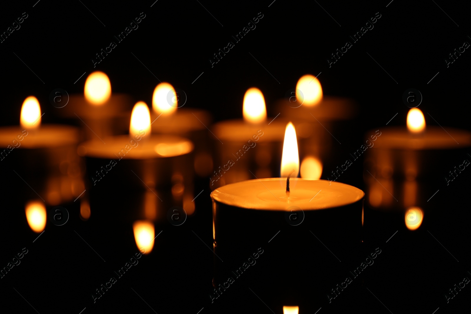 Photo of Many burning candles on dark background, closeup