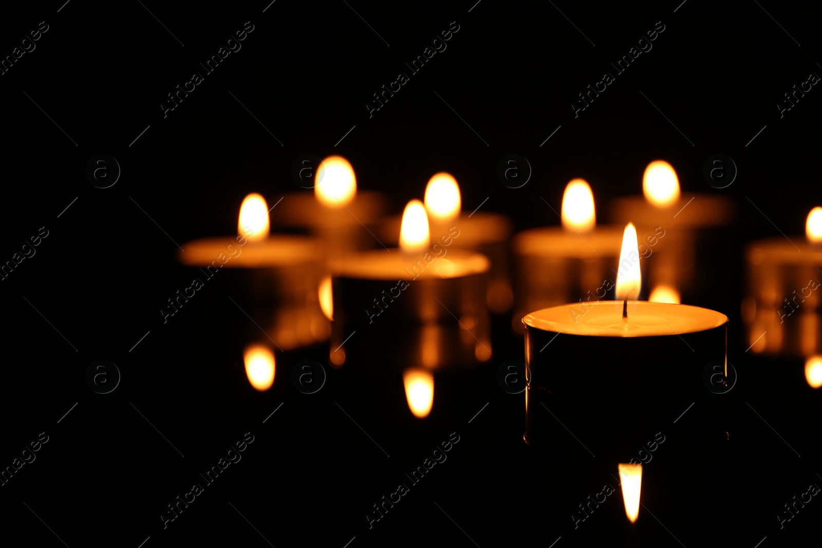 Photo of Many burning candles on dark background, closeup