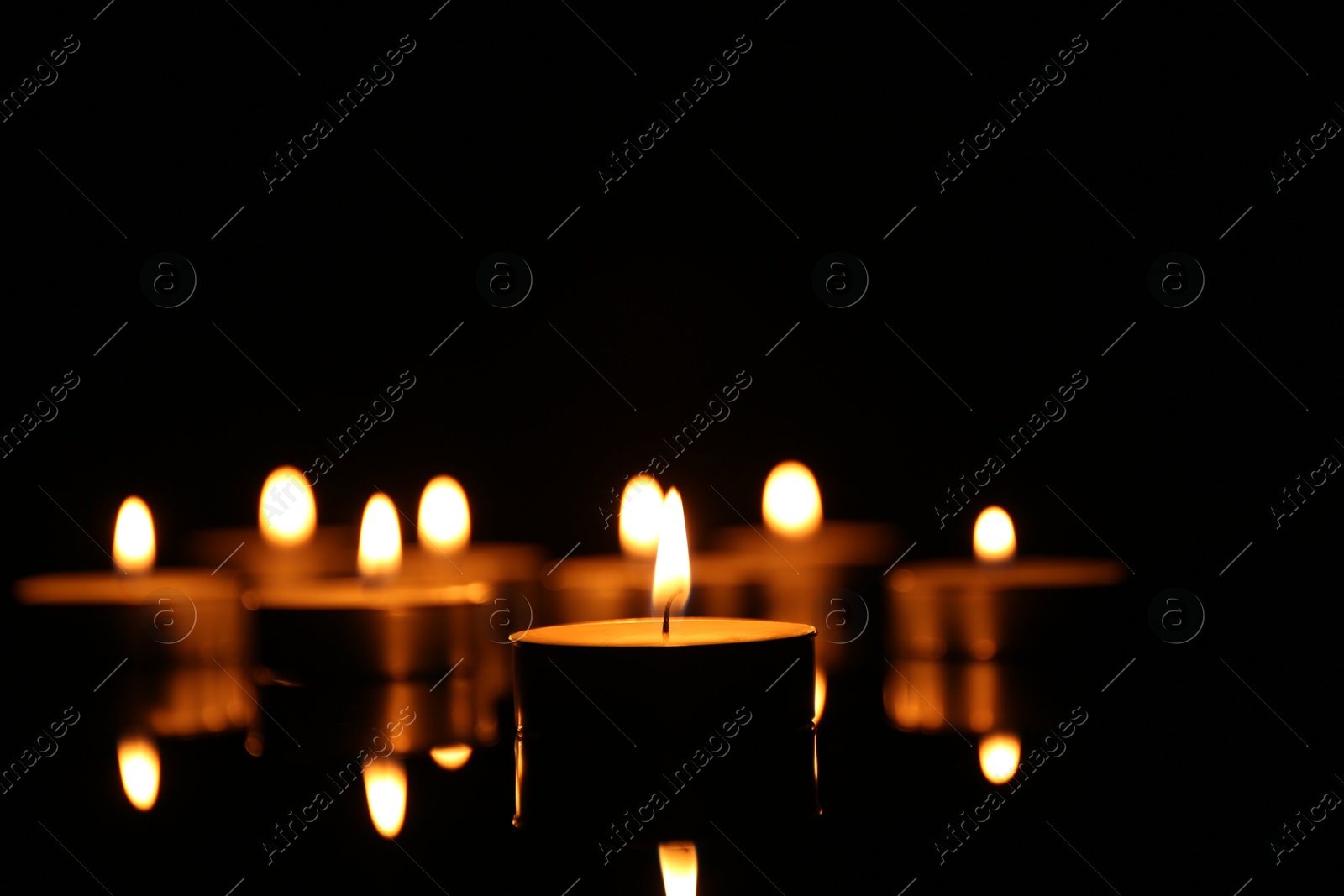 Photo of Many burning candles on dark background, closeup