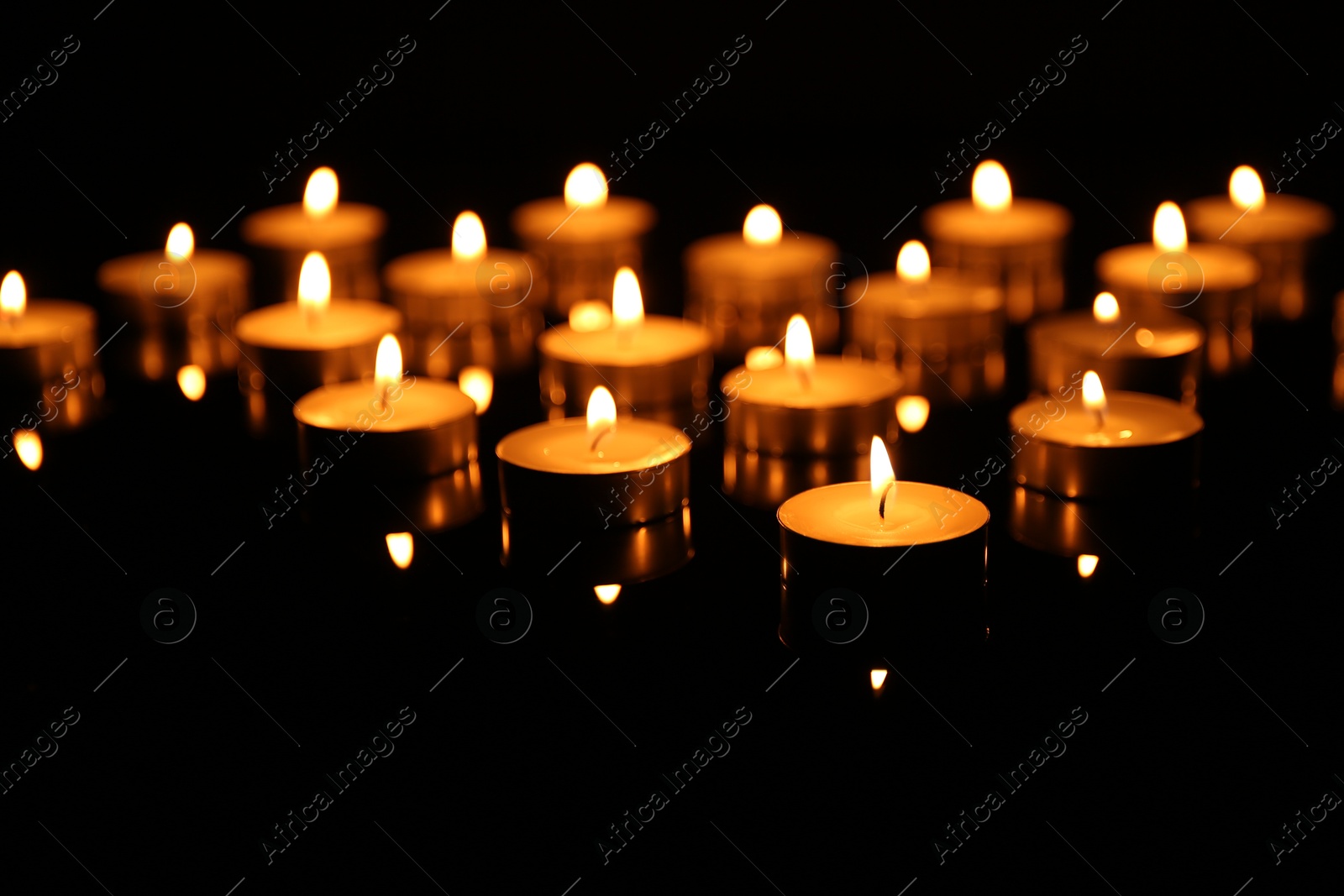 Photo of Many burning candles on dark background, closeup