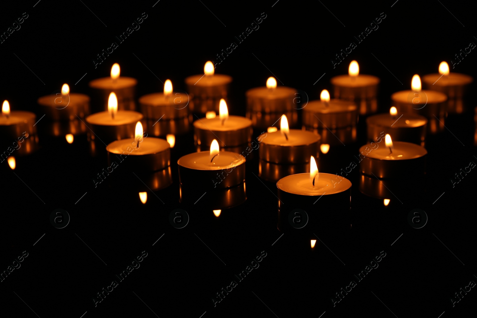 Photo of Many burning candles on dark background, closeup