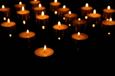 Photo of Many burning candles on dark background, closeup