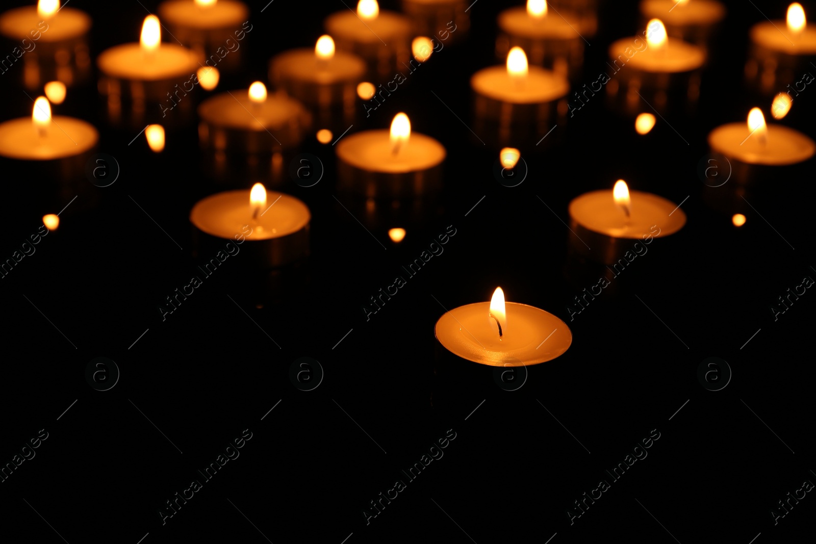 Photo of Many burning candles on dark background, closeup