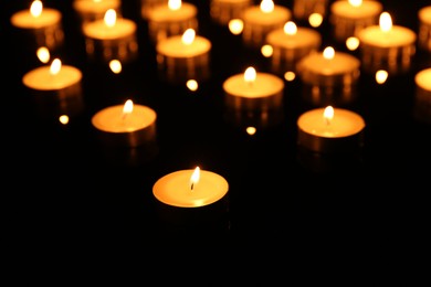 Photo of Many burning candles on dark background, closeup