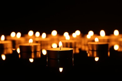 Photo of Many burning candles on dark background, closeup