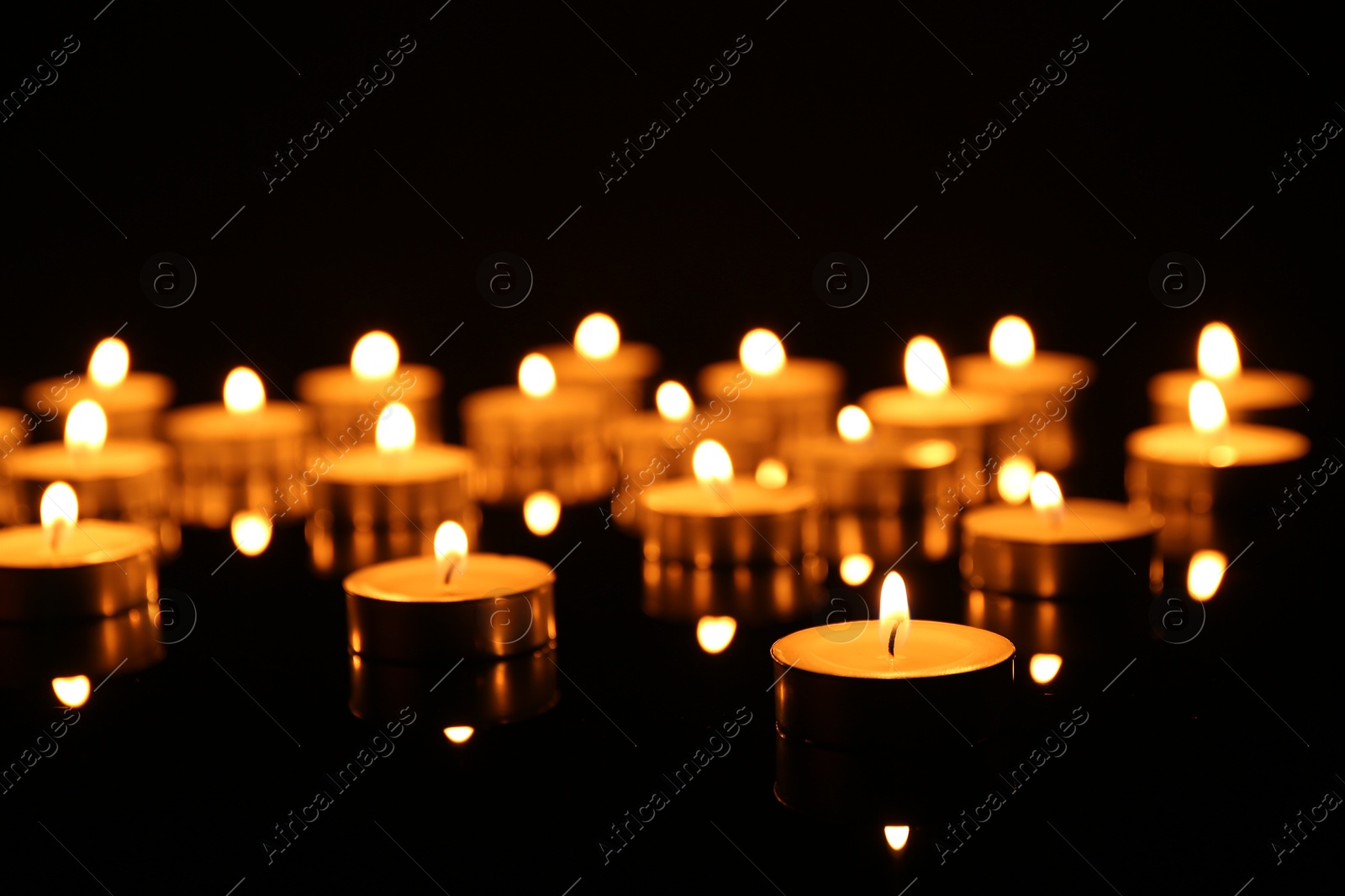 Photo of Many burning candles on dark background, closeup