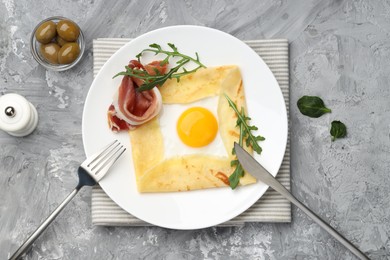 Photo of Delicious crepe bretonne with bacon and arugula served on grey textured table, flat lay