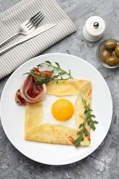 Photo of Delicious crepe bretonne with bacon and arugula served on grey textured table, flat lay