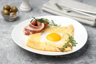 Photo of Delicious crepe bretonne with bacon and arugula on grey textured table, closeup