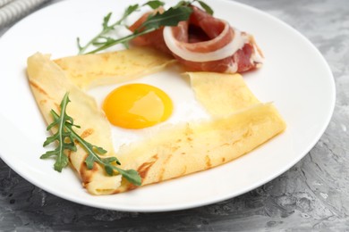 Photo of Delicious crepe bretonne with bacon and arugula on grey textured table, closeup