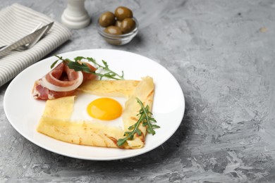 Photo of Delicious crepe bretonne with bacon and arugula on grey textured table. Space for text