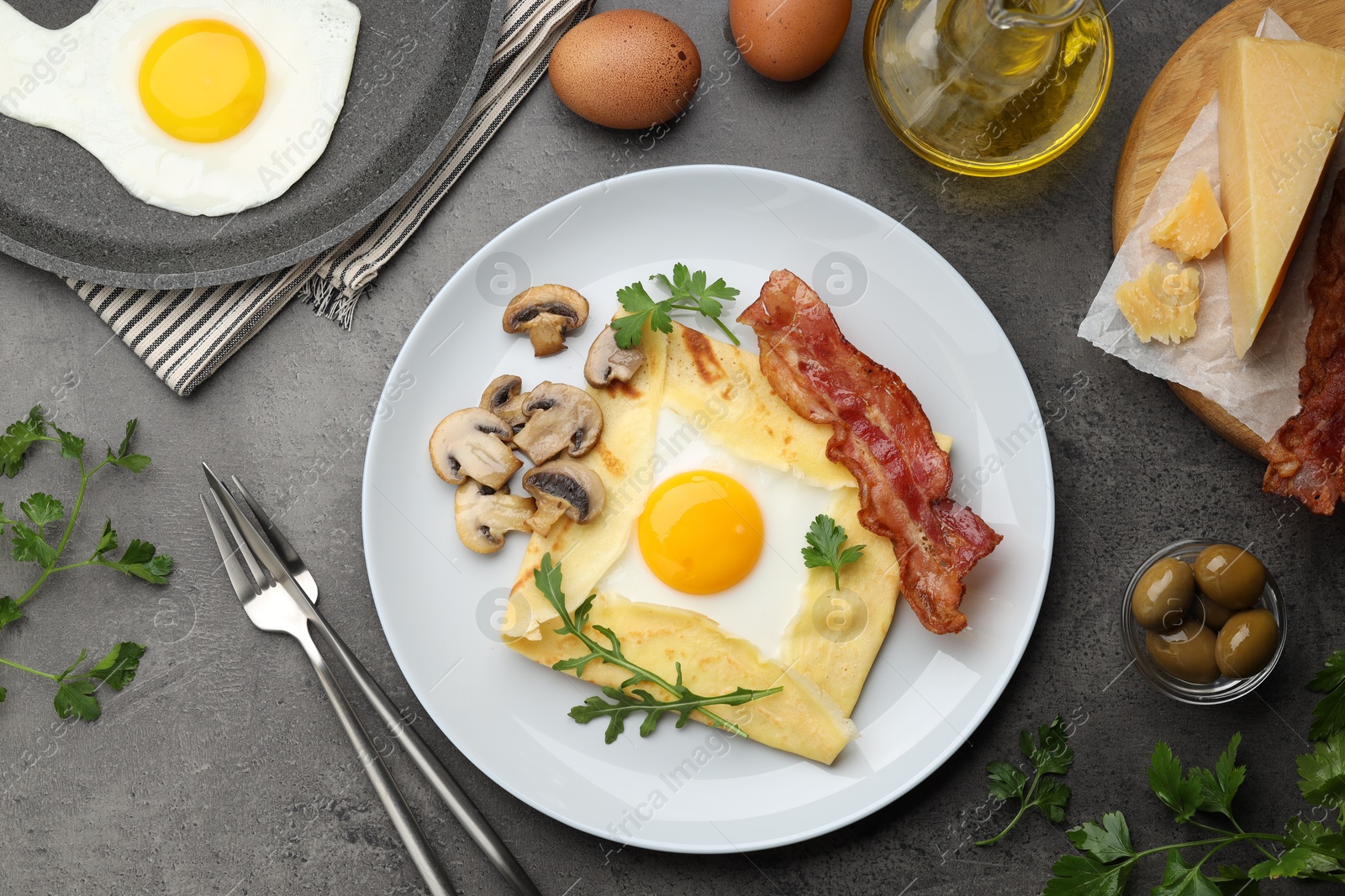 Photo of Delicious crepe bretonne with bacon, mushrooms and arugula served on grey table, flat lay