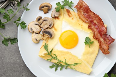 Photo of Delicious crepe bretonne with bacon, mushrooms and arugula on grey table, top view