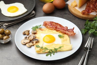 Photo of Delicious crepe bretonne with bacon, mushrooms and arugula served on grey table, closeup