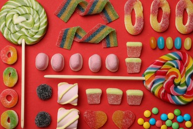 Photo of Different delicious candies and marshmallows on red background, flat lay