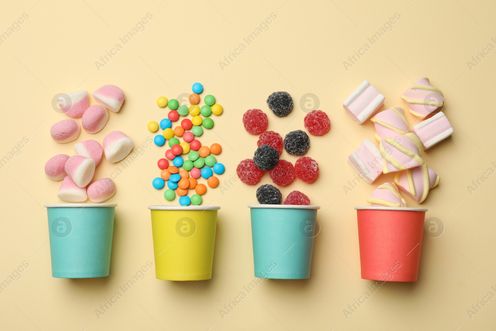 Photo of Different delicious candies and marshmallows on beige background, flat lay