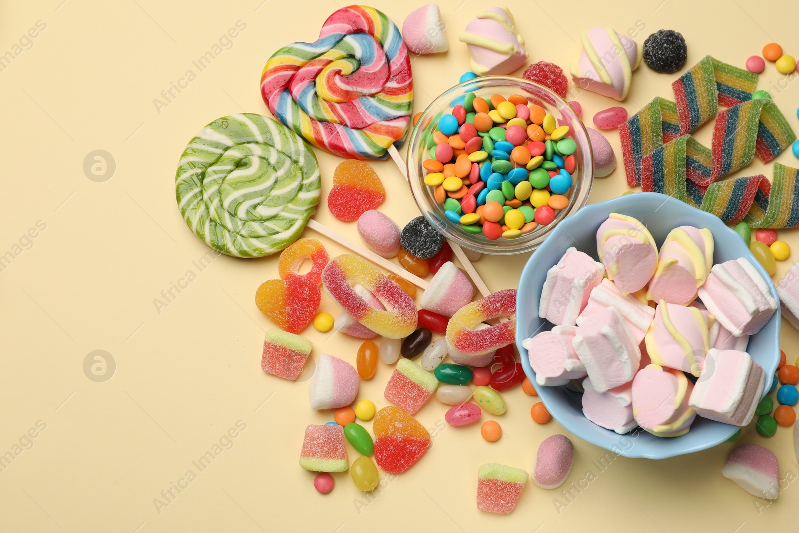 Photo of Different delicious candies and marshmallows on beige background, flat lay