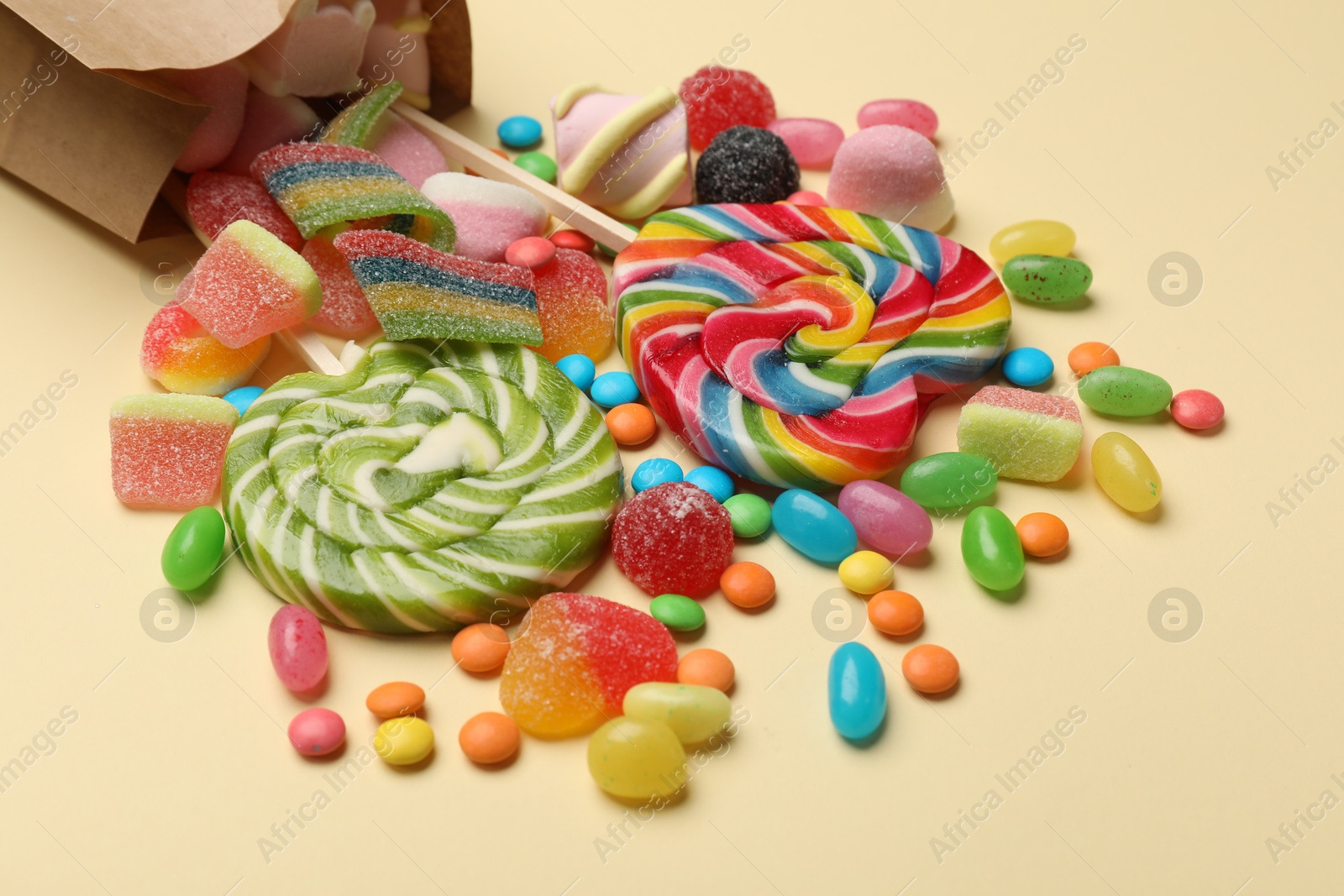 Photo of Different delicious candies and marshmallows on beige background, closeup