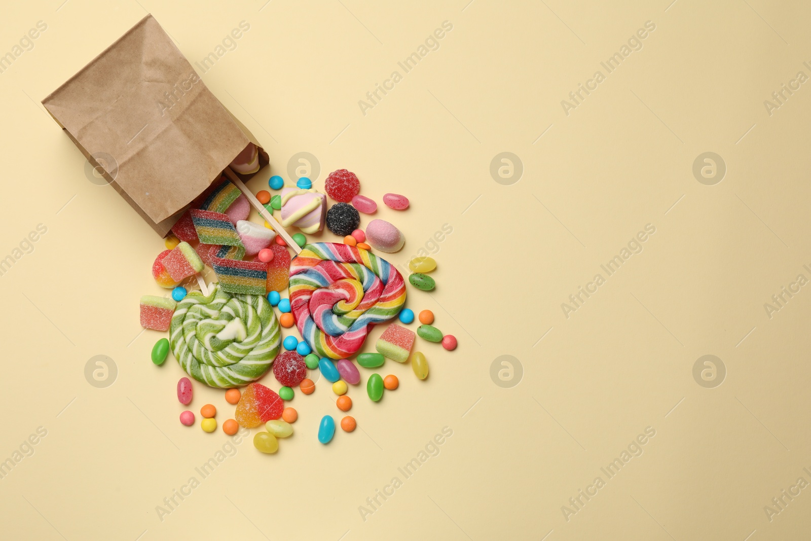 Photo of Different delicious candies and marshmallows on beige background, top view. Space for text